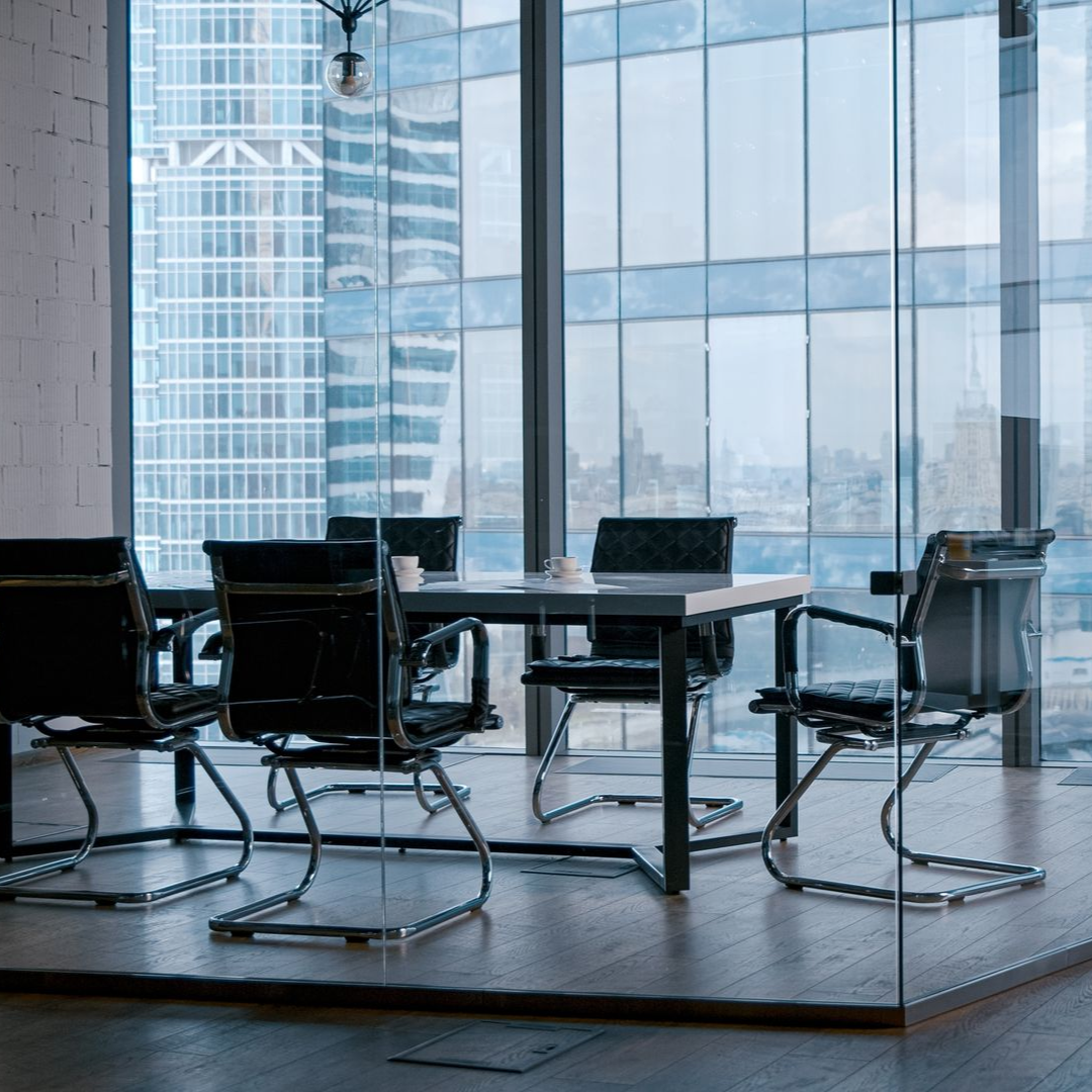 Conference room with table, chairs, and large windows overlooking a cityscape.