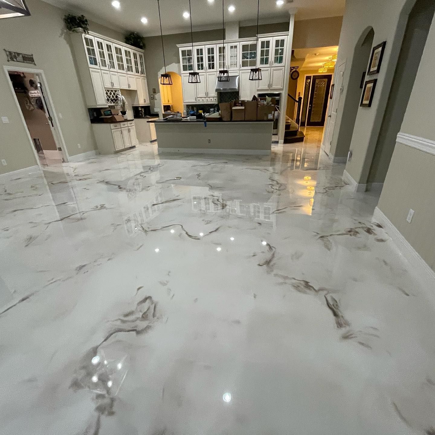 Shiny white and gray epoxy kitchen floor with matching white cabinets.