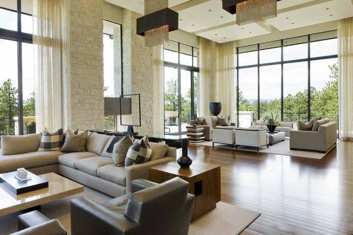 Spacious living room with large windows, neutral tones, wood floors, and modern furniture.