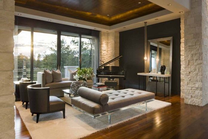 Luxurious living room with piano, seating, large windows, dark accent wall, and wood flooring.