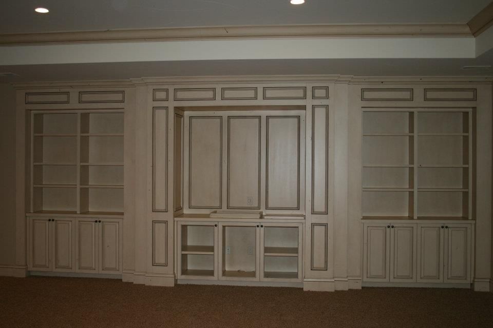 Built-in white cabinets with shelves and doors against a light-colored wall.