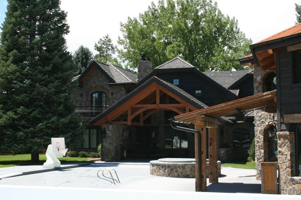 Stone and wood house with a basketball hoop on the driveway.