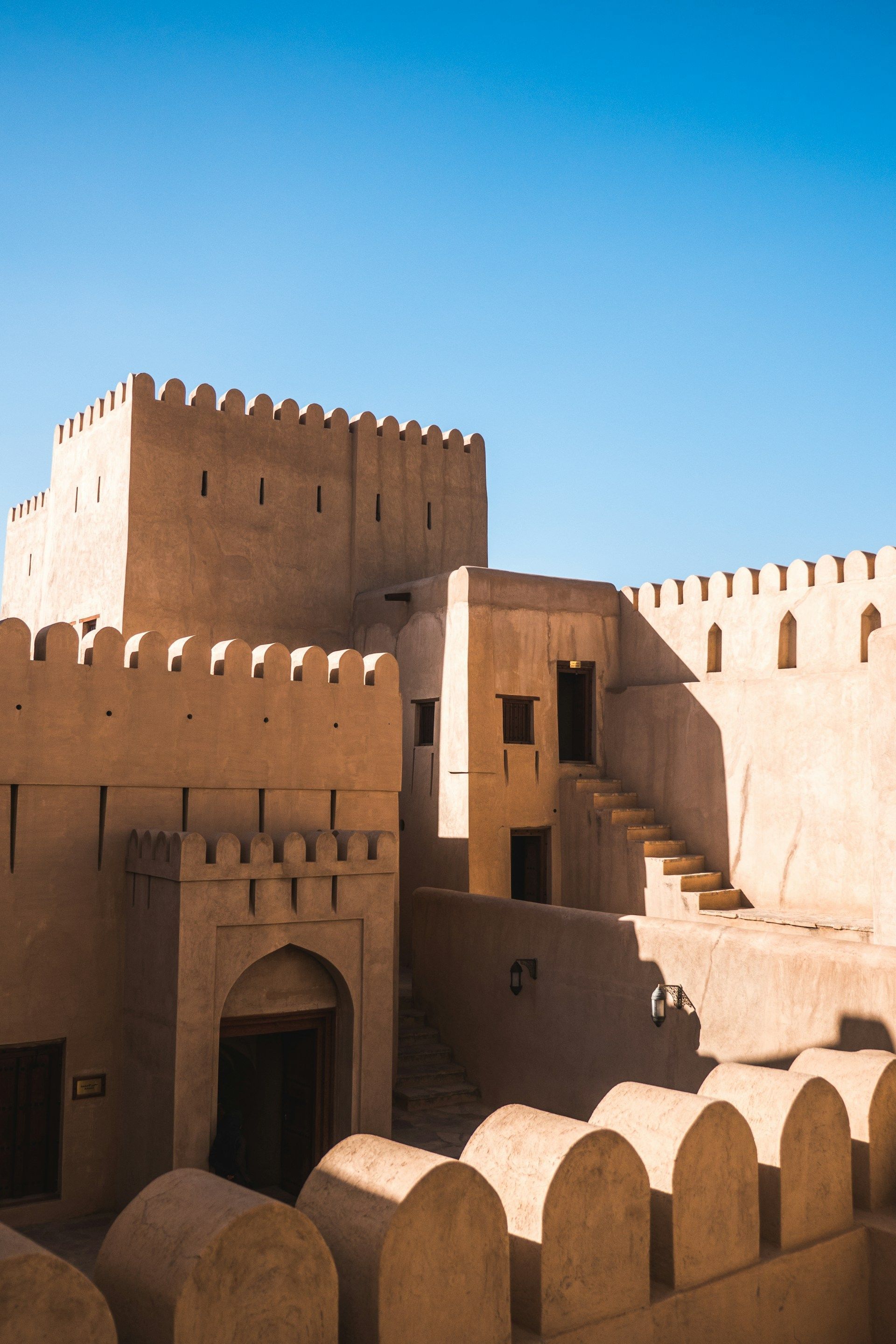 A large building with stairs leading up to it and a blue sky in the background.