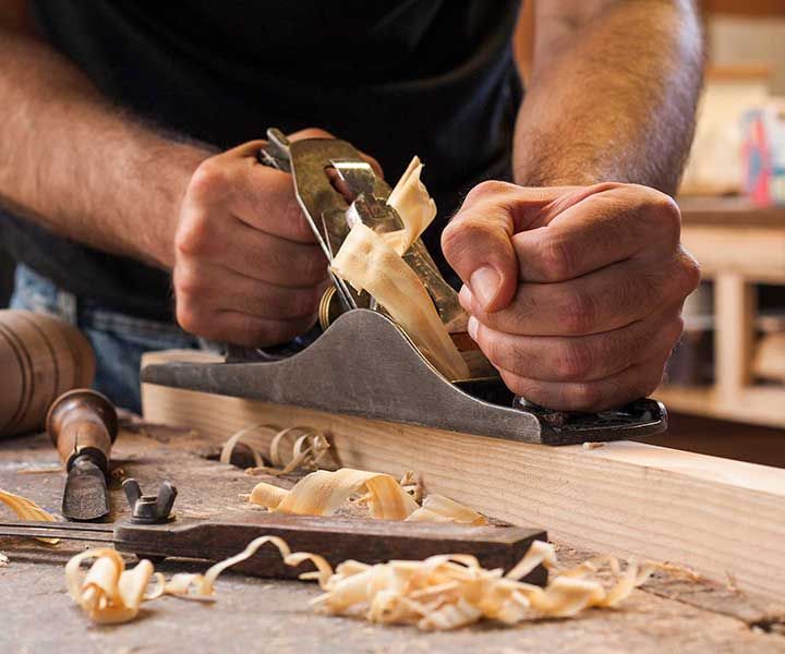 carpenter working with plane on wooden background