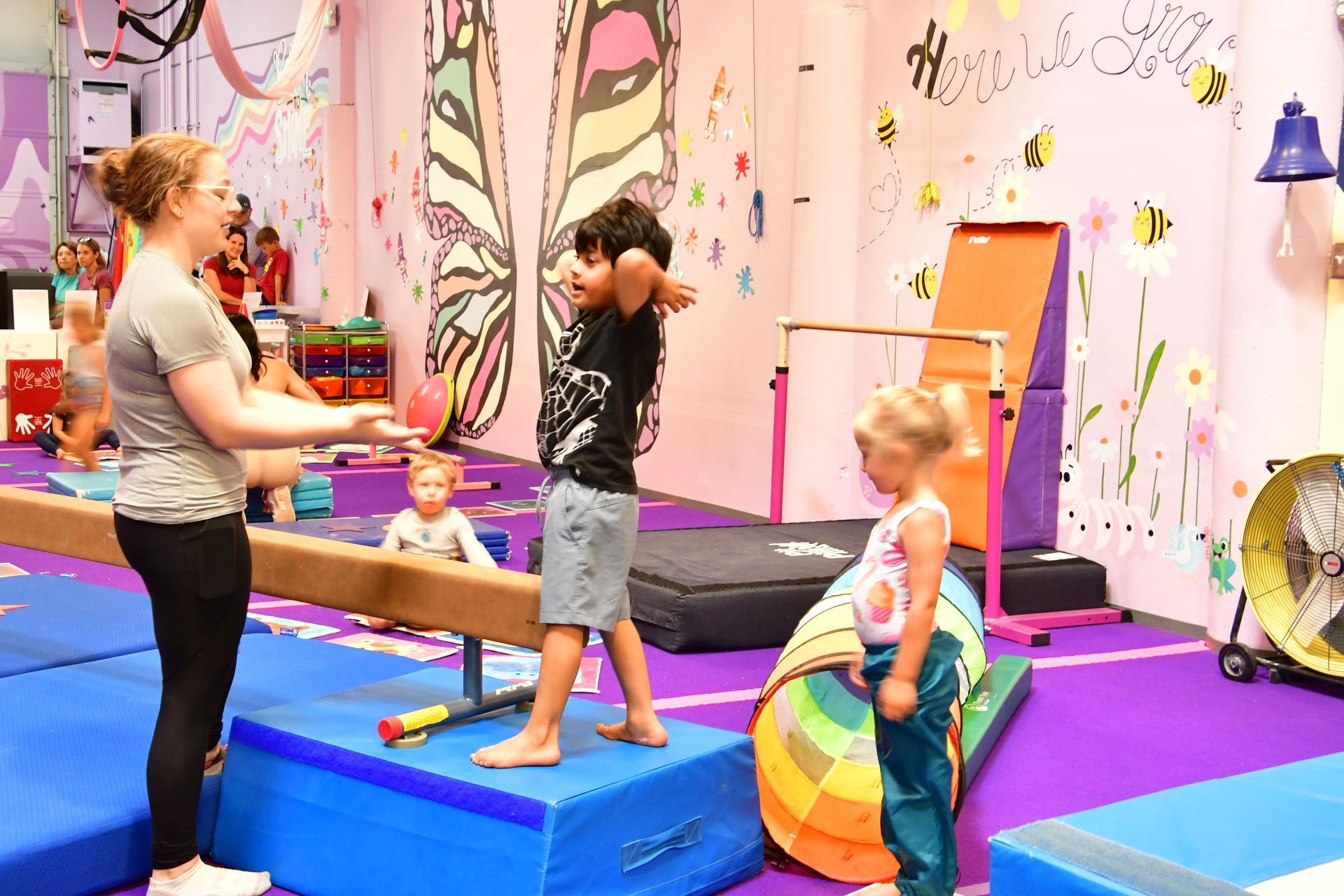 Preschool coach with grey t-shirt explaining a drill to a young boy and girl