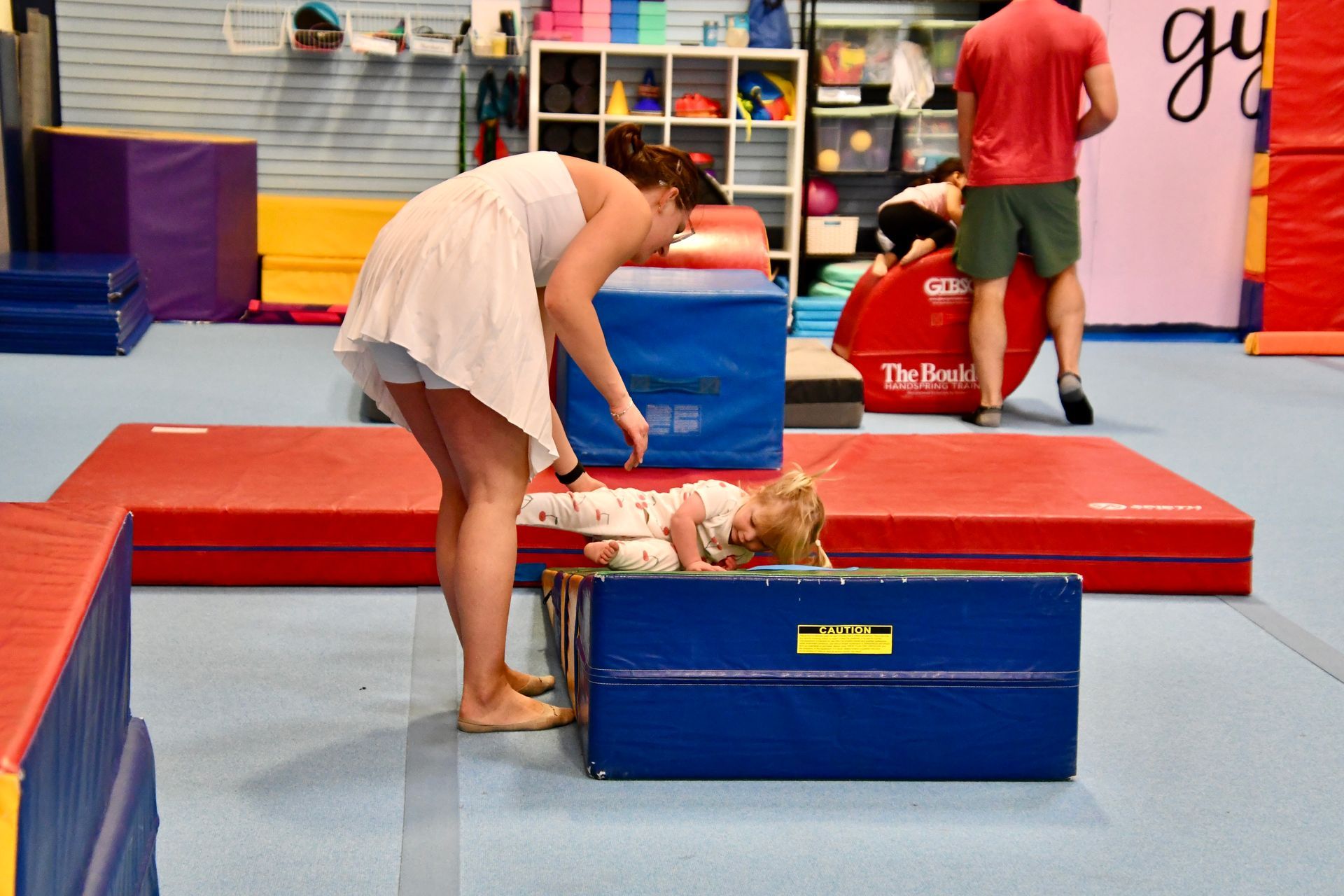 A picture of preschool coach assisting child with cartwheel