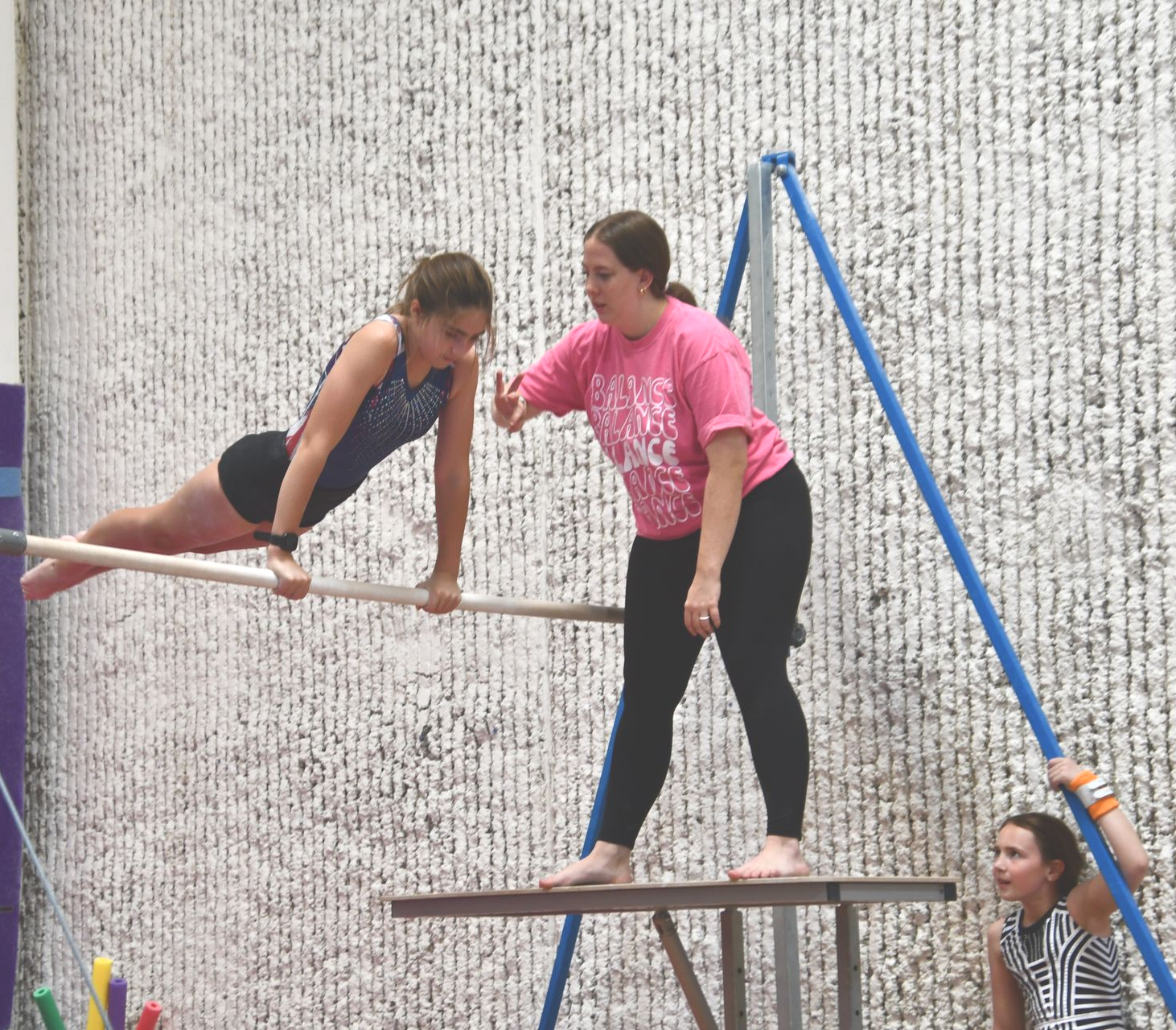 A coach helping a gymnast on the high bar