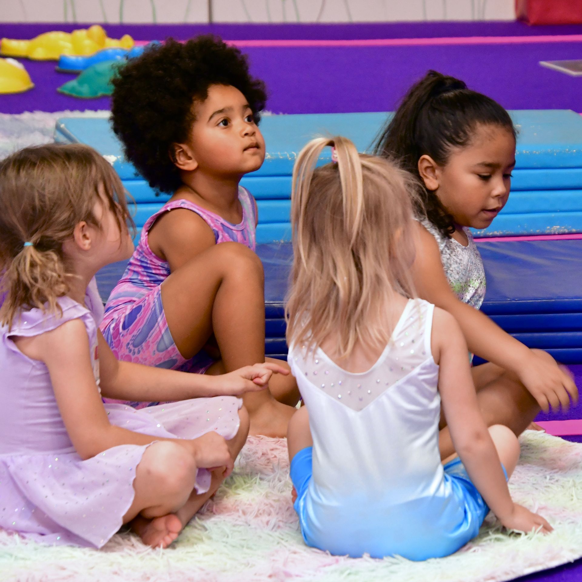 A picture of 4 preschool children listening to their coach