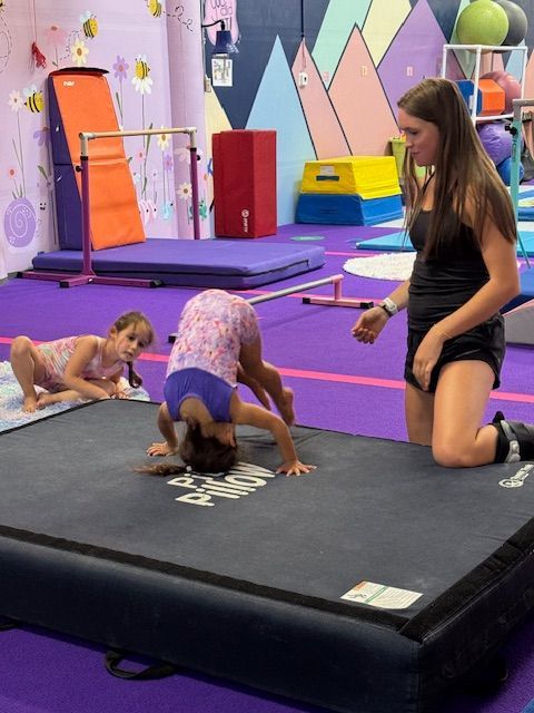 A coach helping preschool students with tumbling