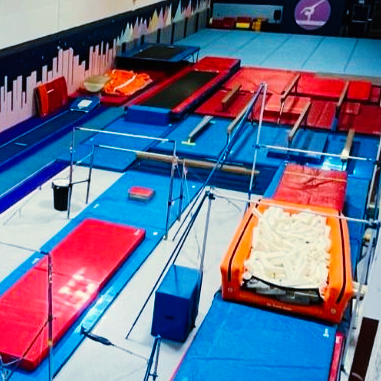 The beam, floor and Tumble Track is shown with decorative wall of mountains and the city skyline in the back