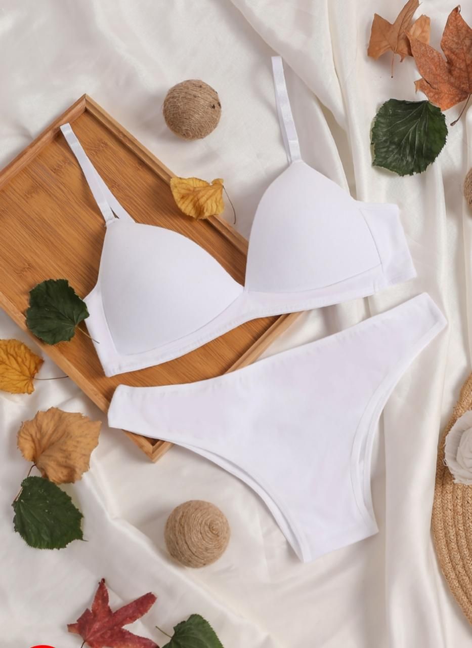Un conjunto de sujetador y ropa interior blancos está sobre una tela blanca.