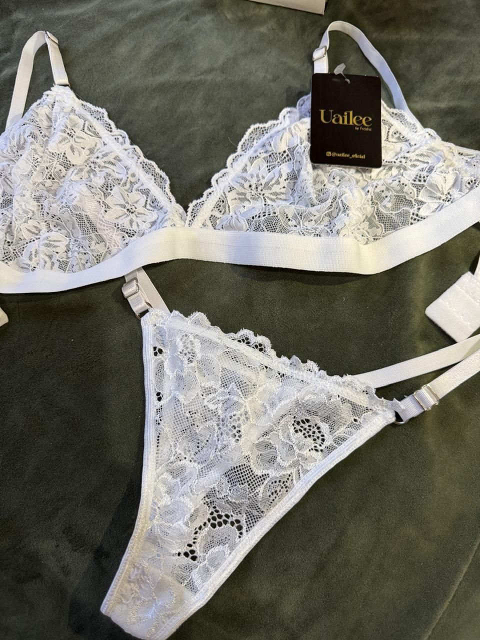 Un conjunto de sujetador y tanga de encaje blanco con una etiqueta.