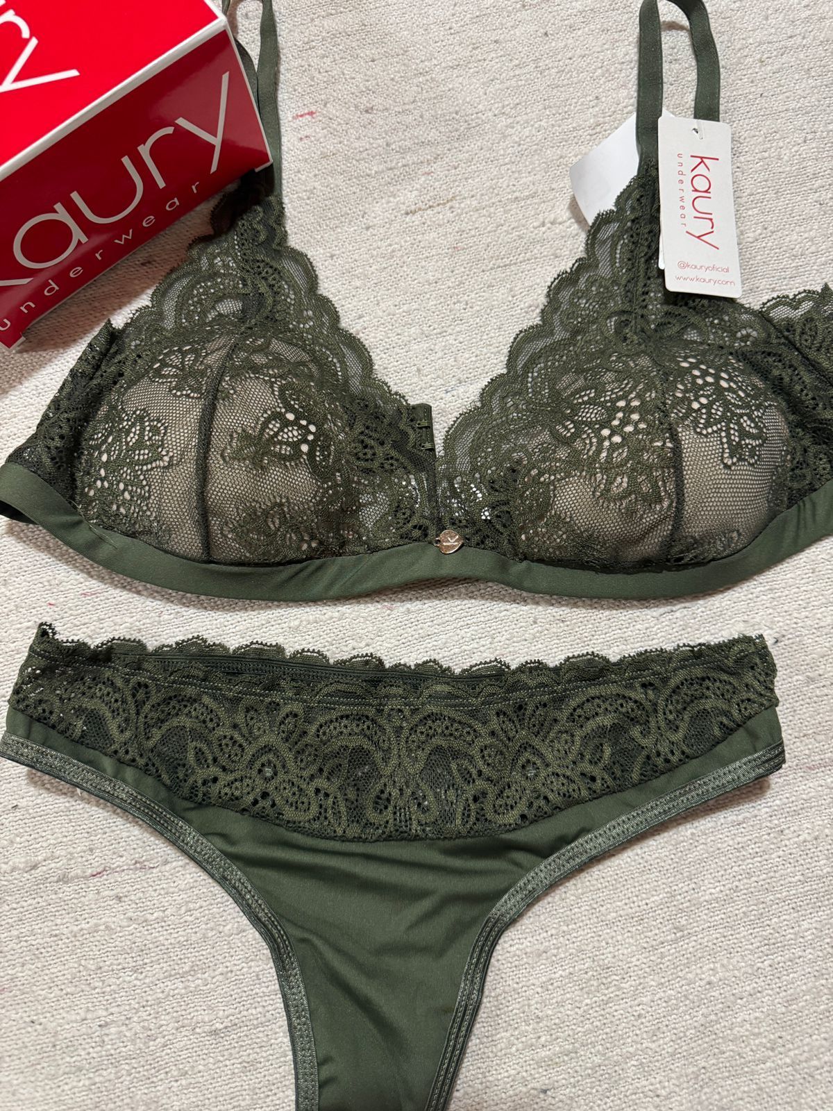 Un conjunto de sujetador y tanga de encaje verde con un cuadro rojo en el fondo.