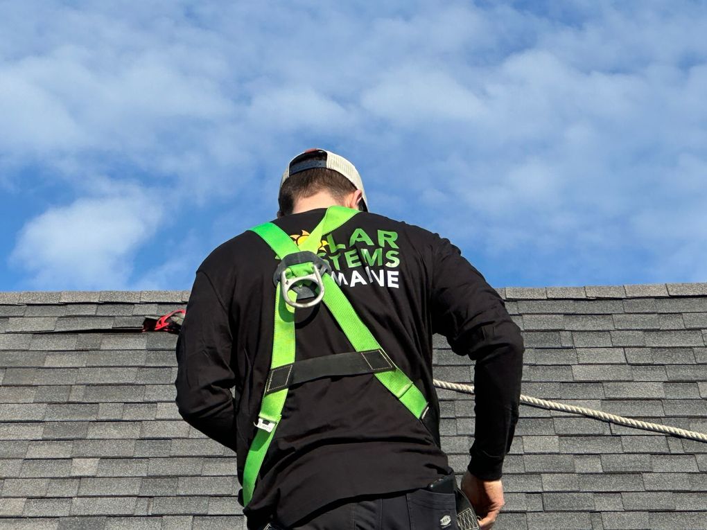 A man wearing a green harness is standing on top of a roof.