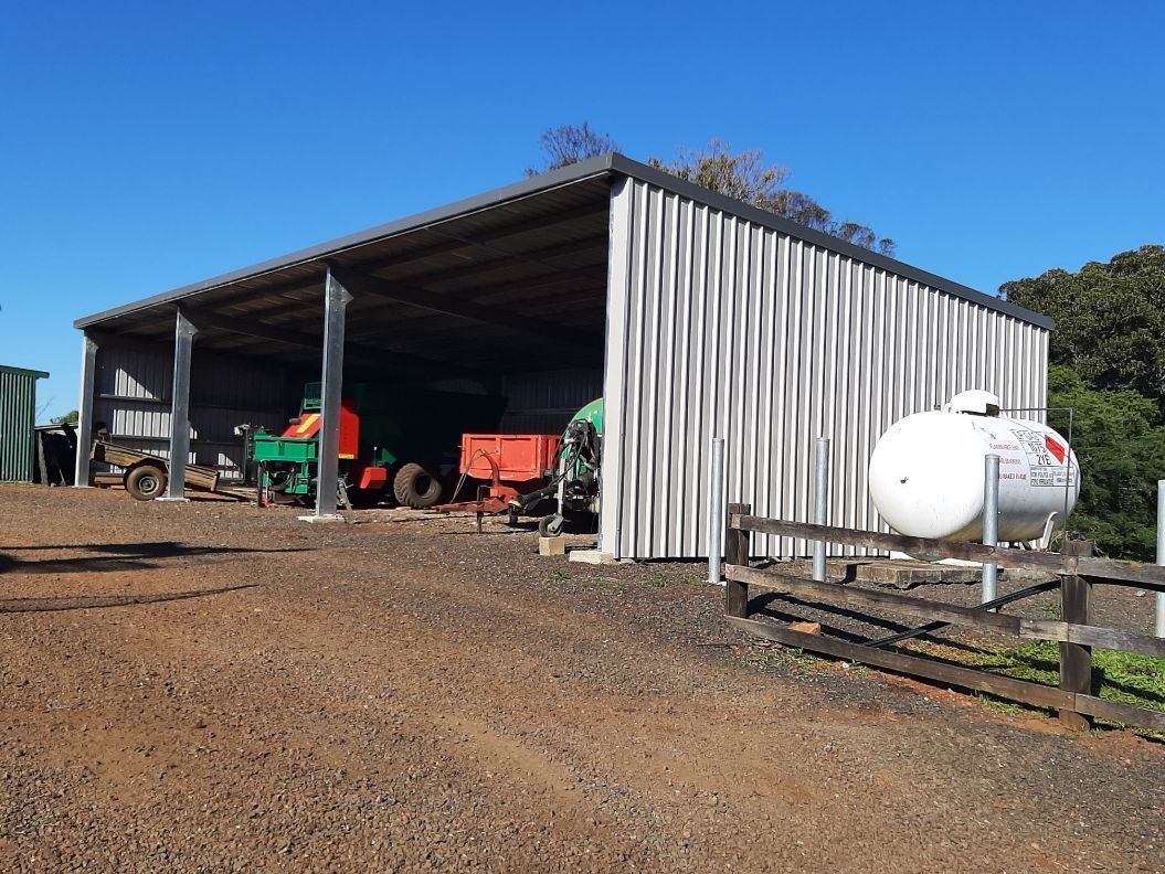 Metal Shed with an Excavator Parked Inside — Shed Kits in Lismore, NSW