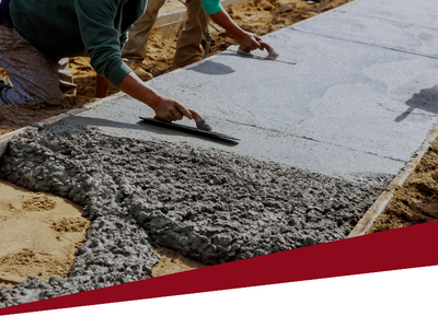 Workers smoothing wet concrete on a sidewalk construction site