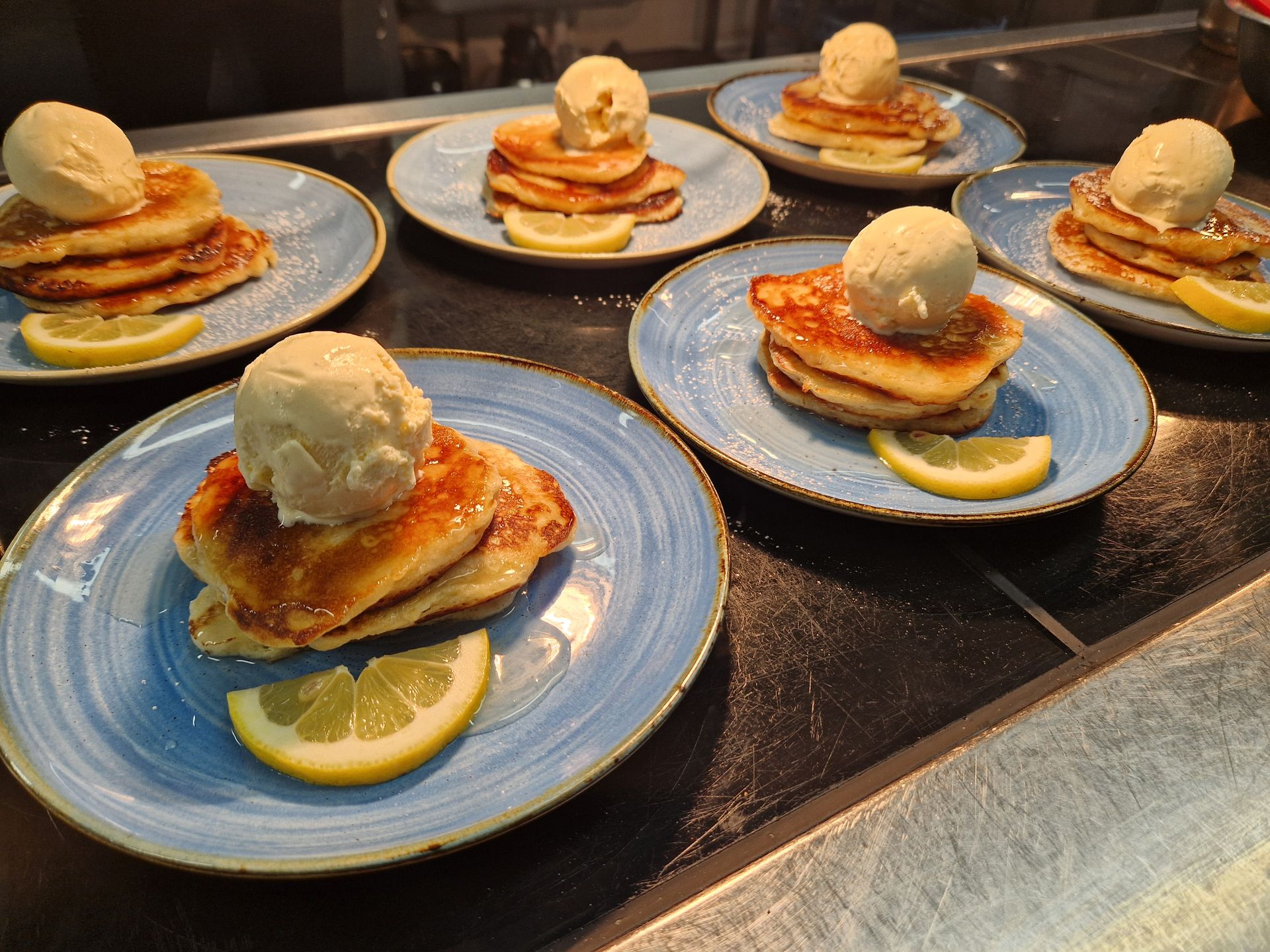Plated pancakes with ice cream and lemon garnish prepared for students, showcasing high‑quality school catering.