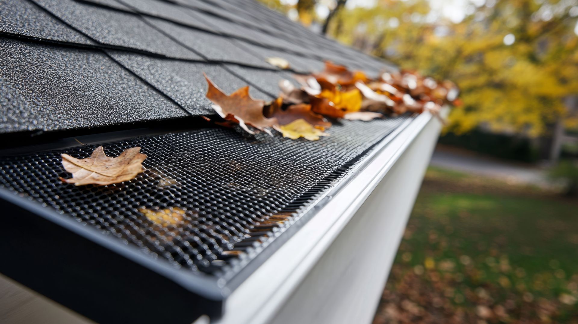 Blue-tiled roof corner with white gutter and downspout on a brick house