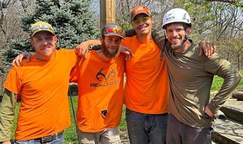A group of men wearing orange shirts and helmets are posing for a picture.