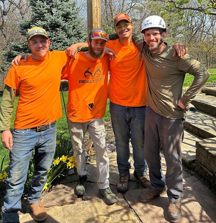 Four men wearing orange shirts are posing for a picture