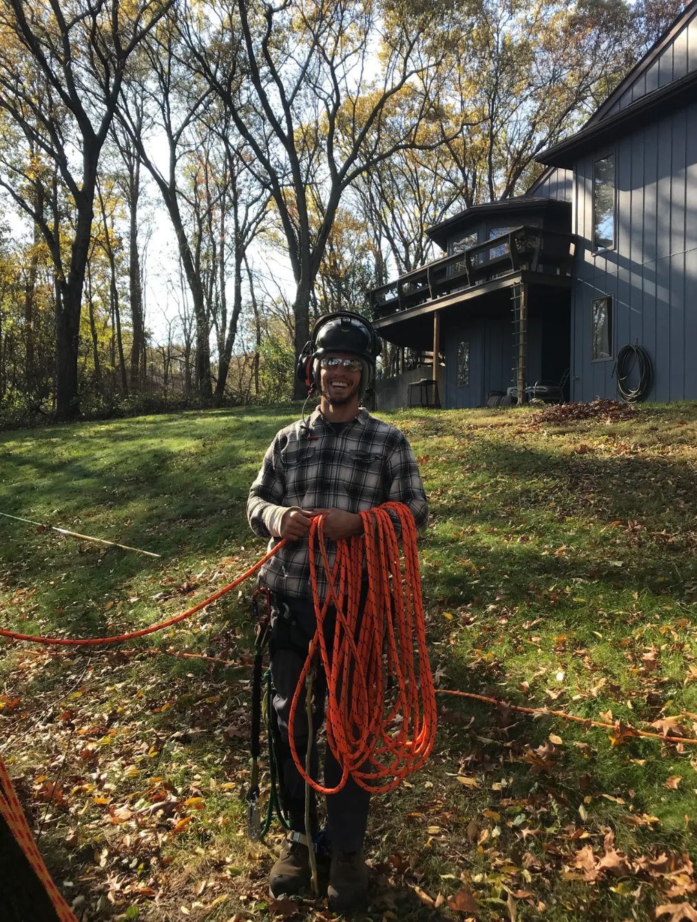 A man is holding an orange rope in front of a house.