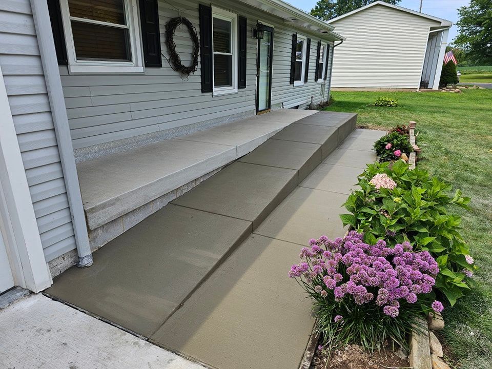Concrete ramp leading up to a house entrance, with flower beds on the right.