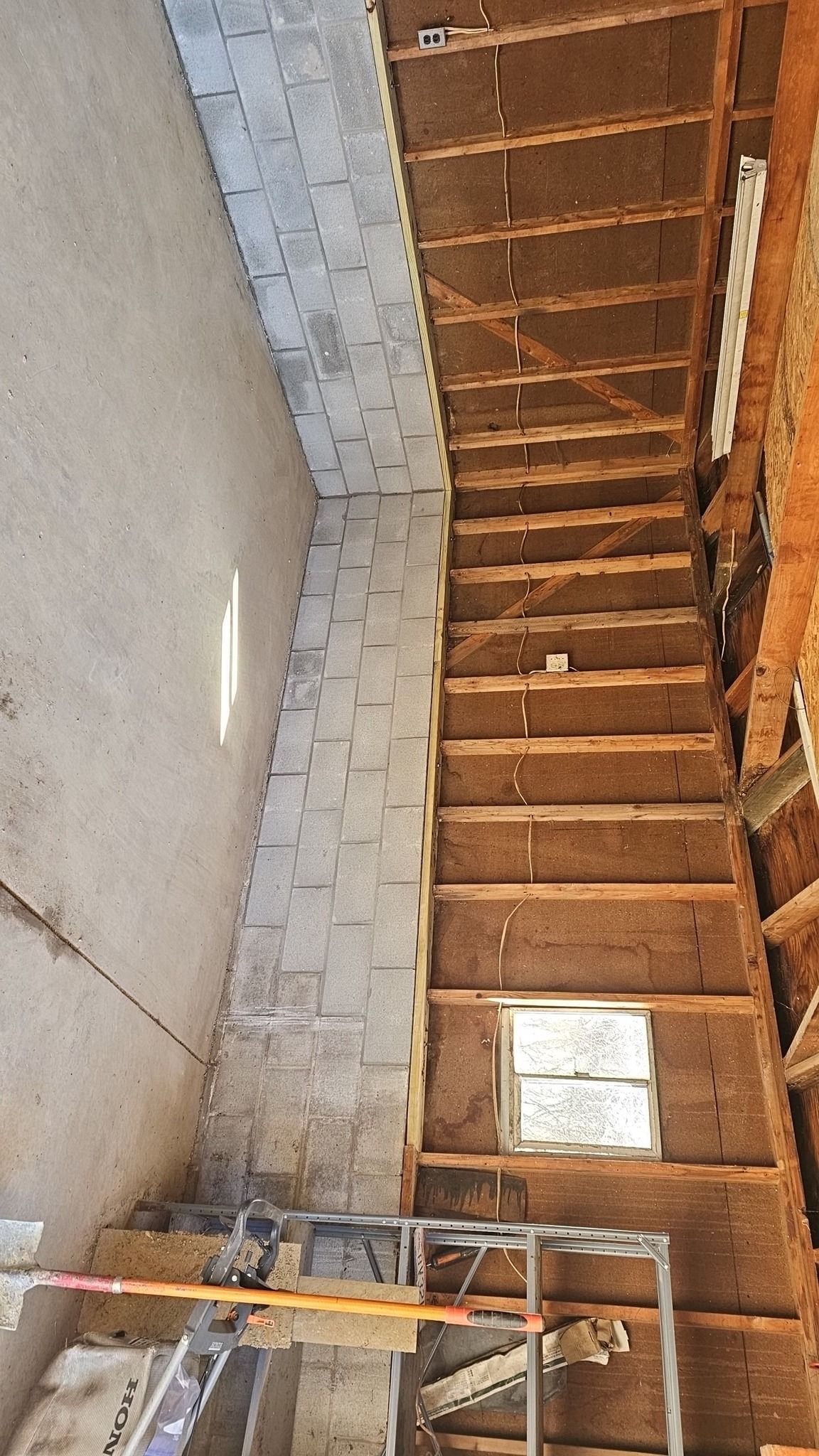 Staircase under construction with exposed wooden framework and a concrete wall.
