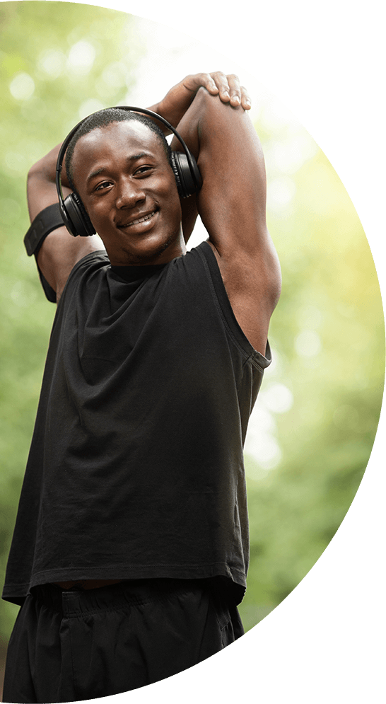 A man wearing headphones is stretching his arms.