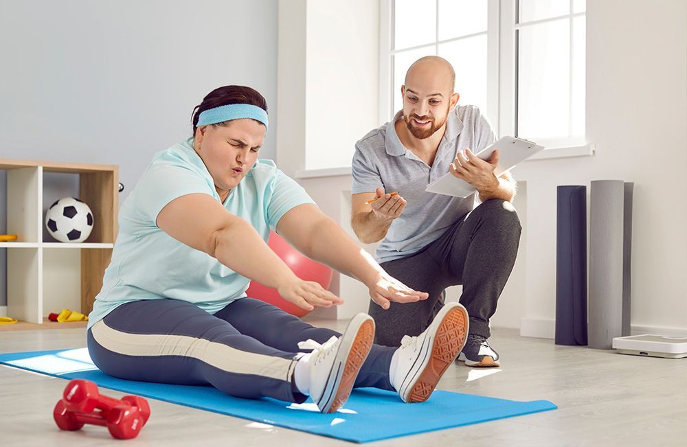 A man is talking to a woman who is sitting on a yoga mat.