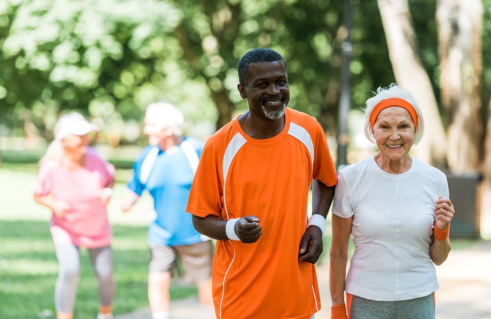 A group of elderly people are jogging in a park.