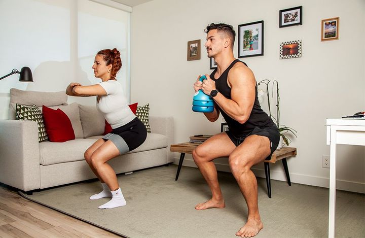 A man and a woman are squatting in a living room.