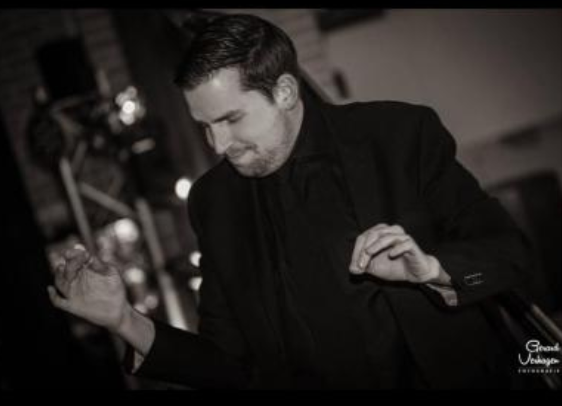 Man in zwart pak, die handgebaren maakt, draait muziek op een evenement.