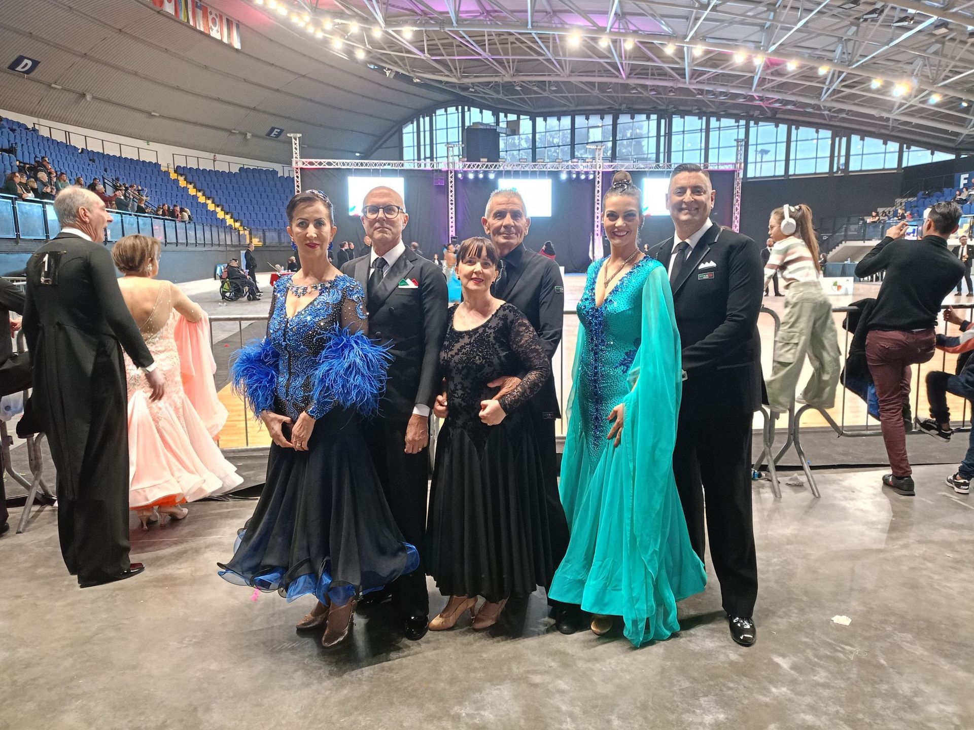 Gruppo di ballerini da sala in abiti formali che posano in un'arena.