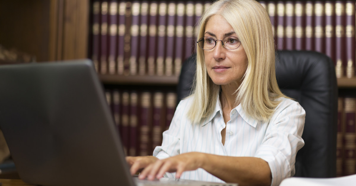 A woman is sitting at a desk using a laptop computer.