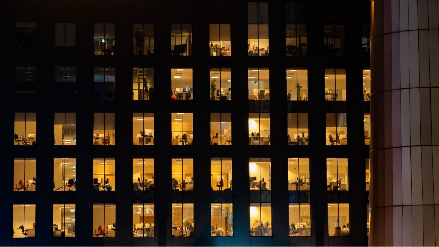 Office building at night with some offices lit up, and some dark
