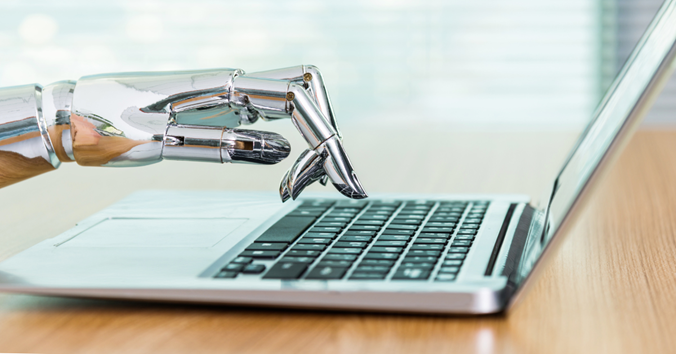 A robotic hand is typing on a laptop computer.