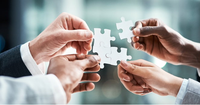 Four business people connecting jigsaw puzzle pieces.
