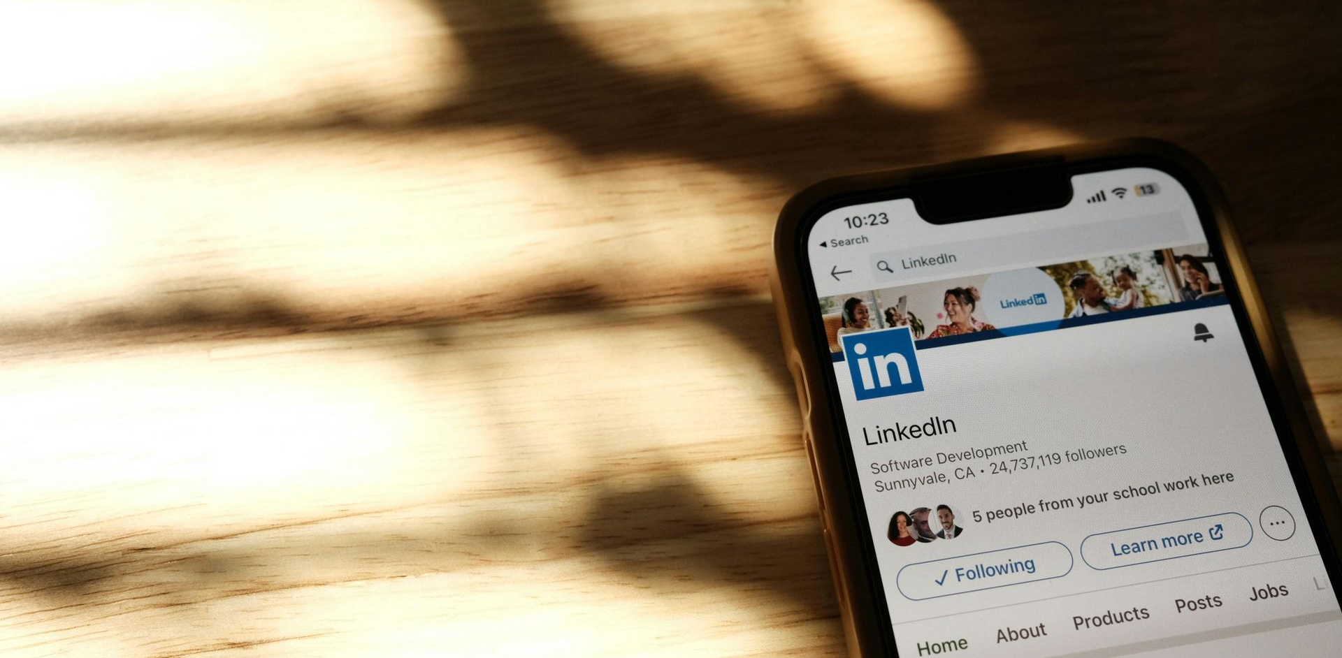 Mobile phone lying on a desk. The screen is showing a LinkedIn profile