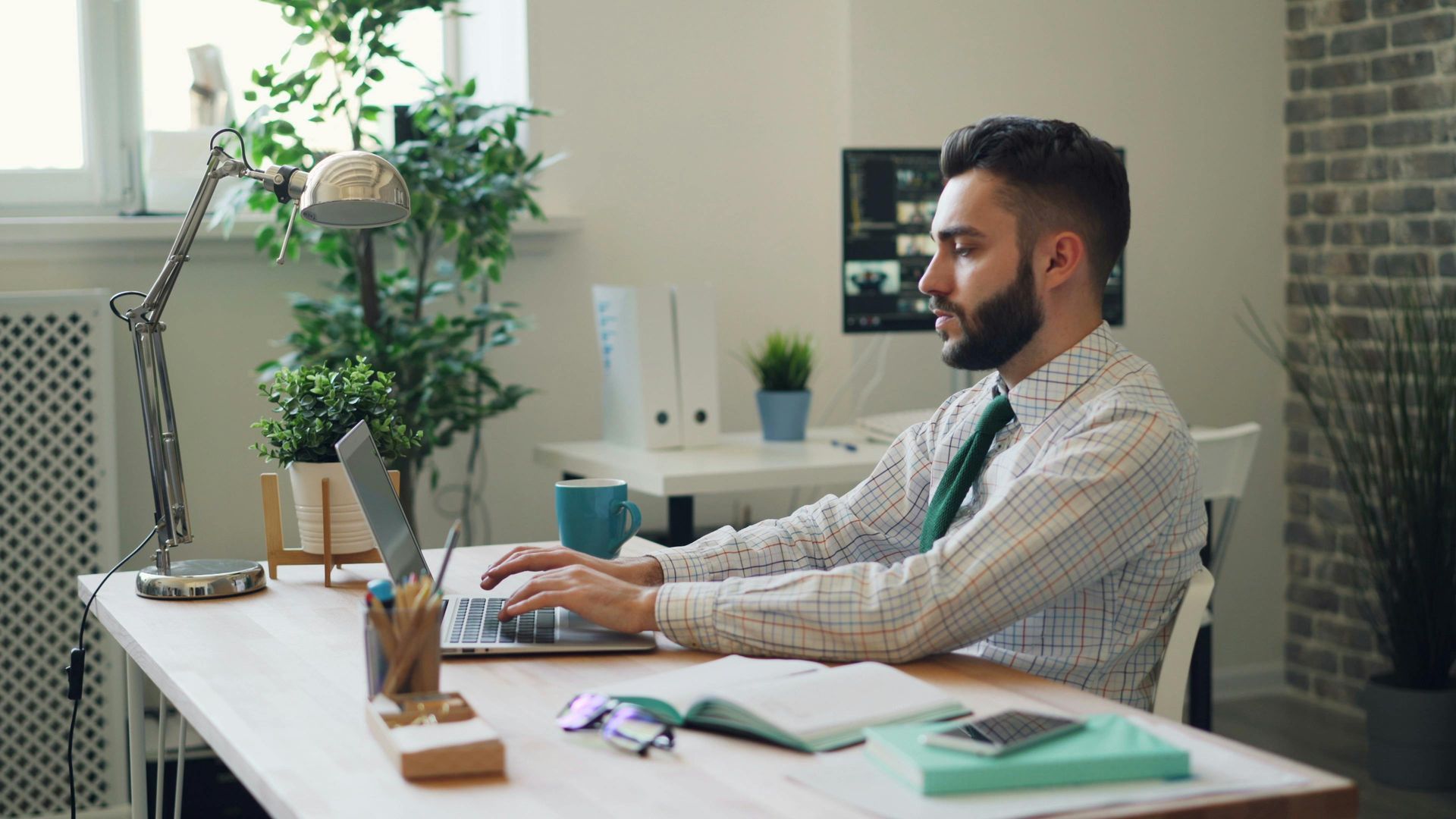 A person sitting at a desk typing on their laptop