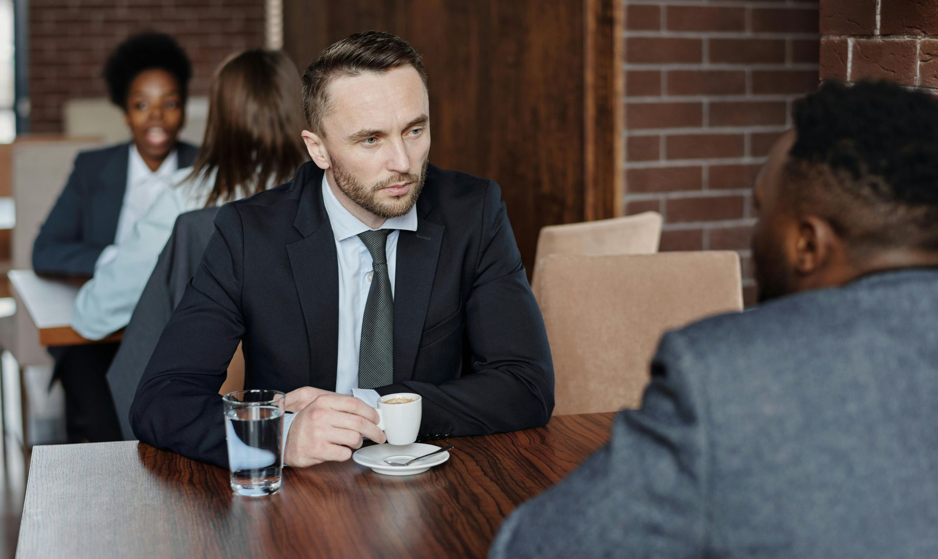 Two people in suits meeting over coffee at a cafe