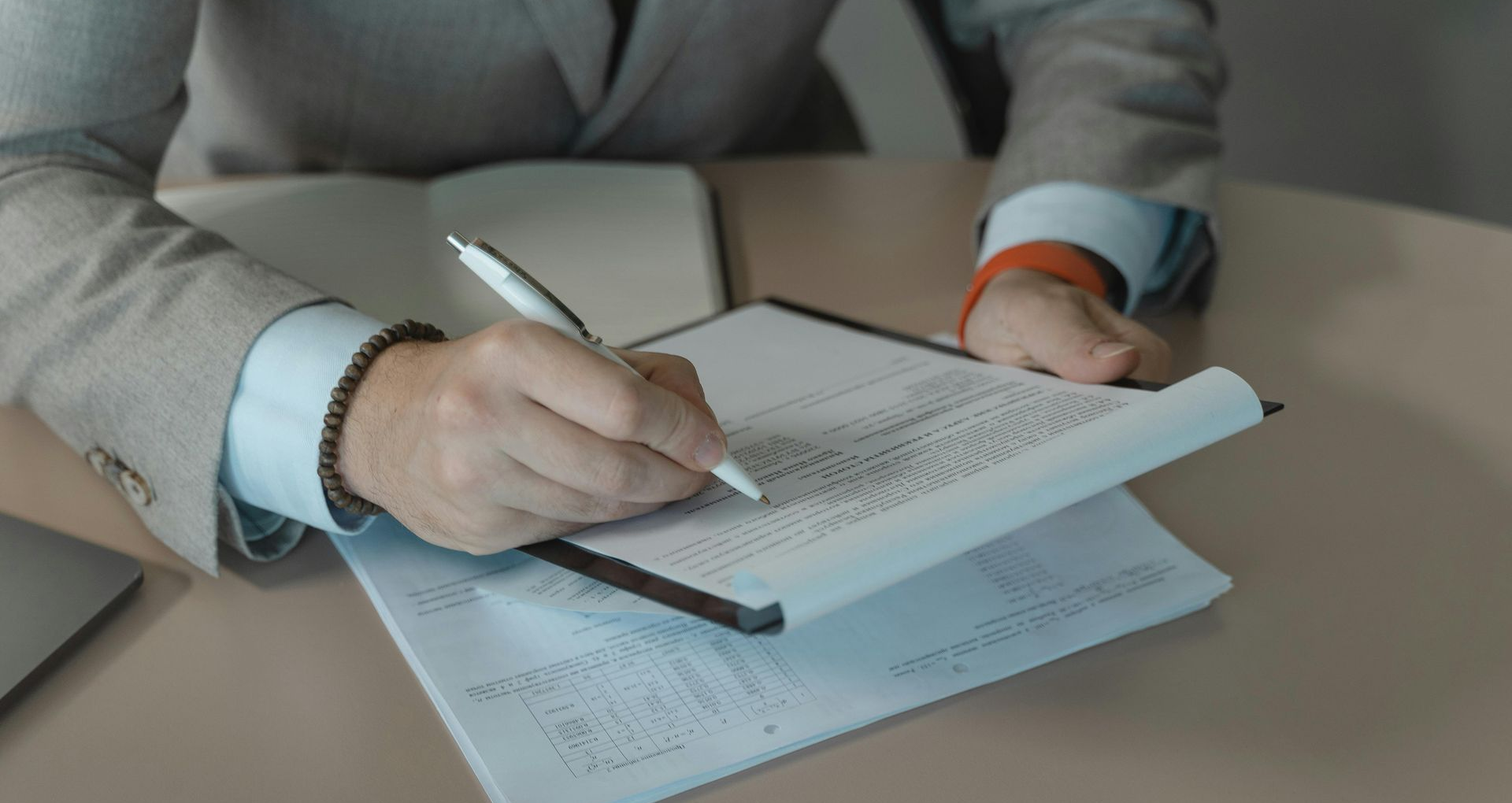 Man in grey suit writing on a clipboard