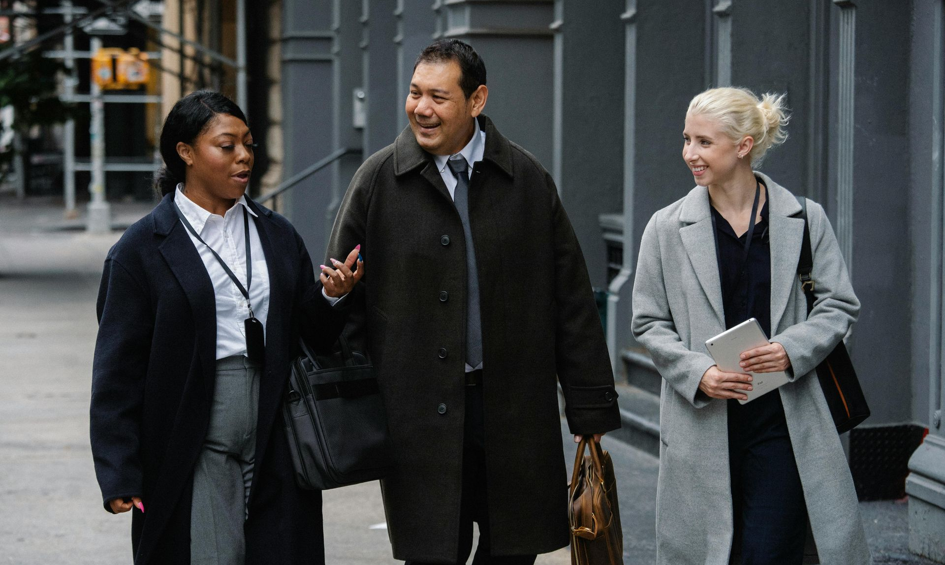 3 colleagues in suits walking and talking outside city office buildings
