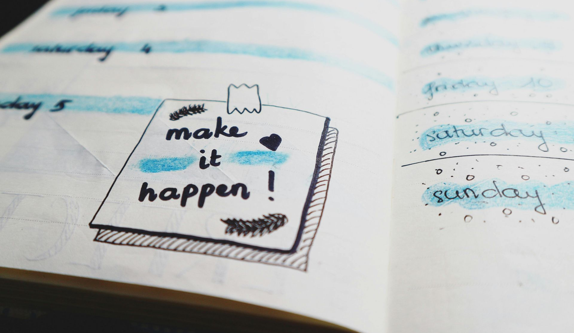 An open note book with the words 'make it happen!' written in it