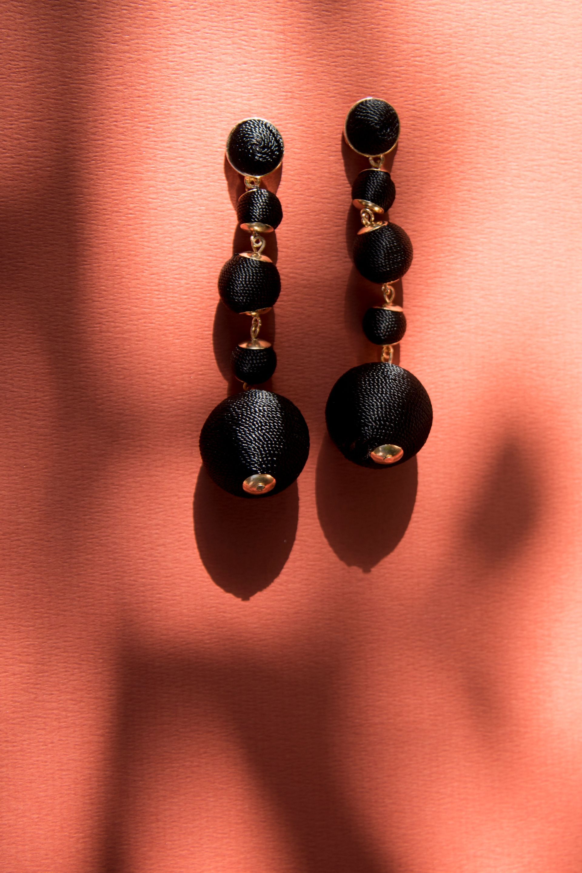 Een paar zwarte oorbellen liggen op een rood oppervlak.