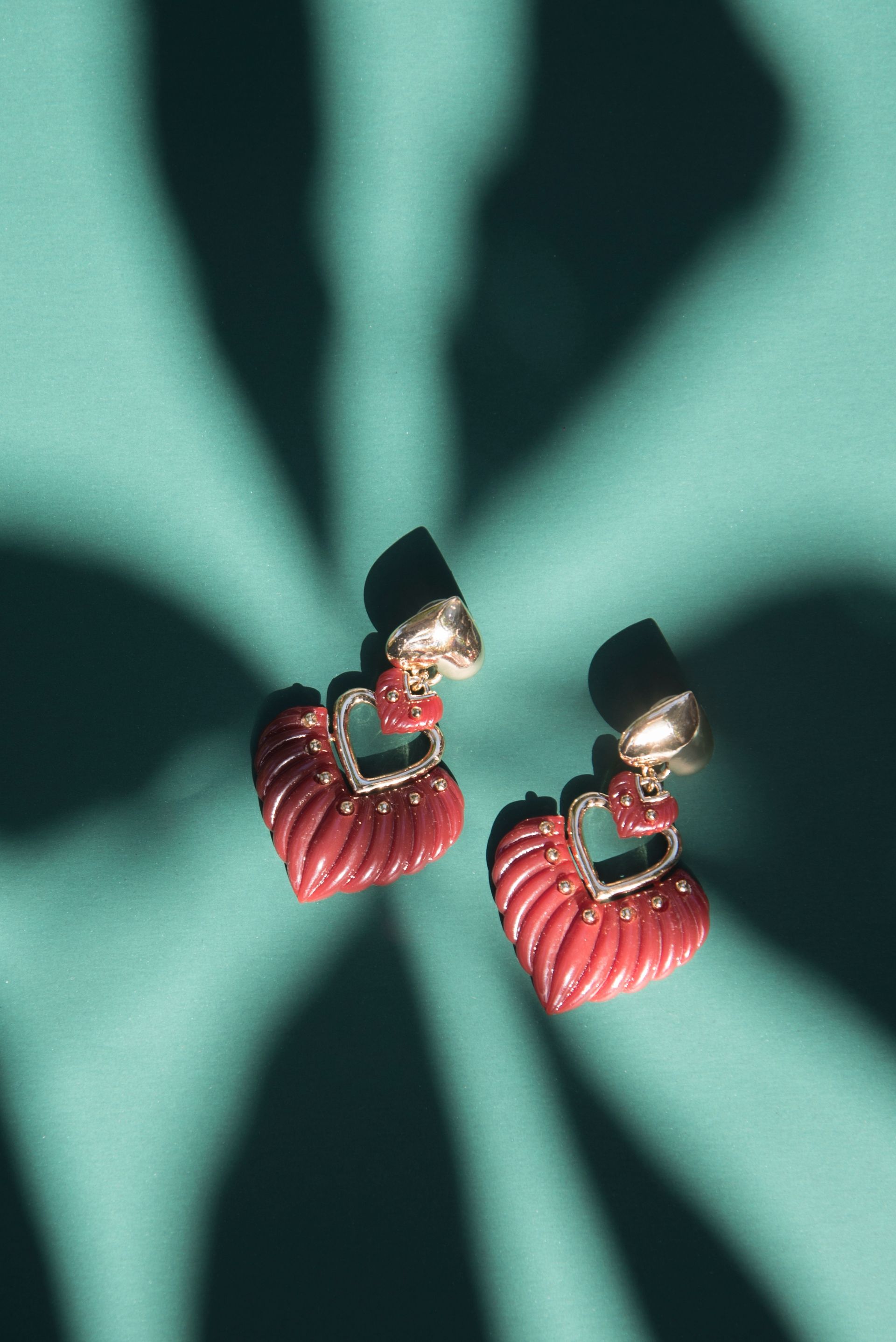 Een paar rode oorbellen liggen op een groen oppervlak.