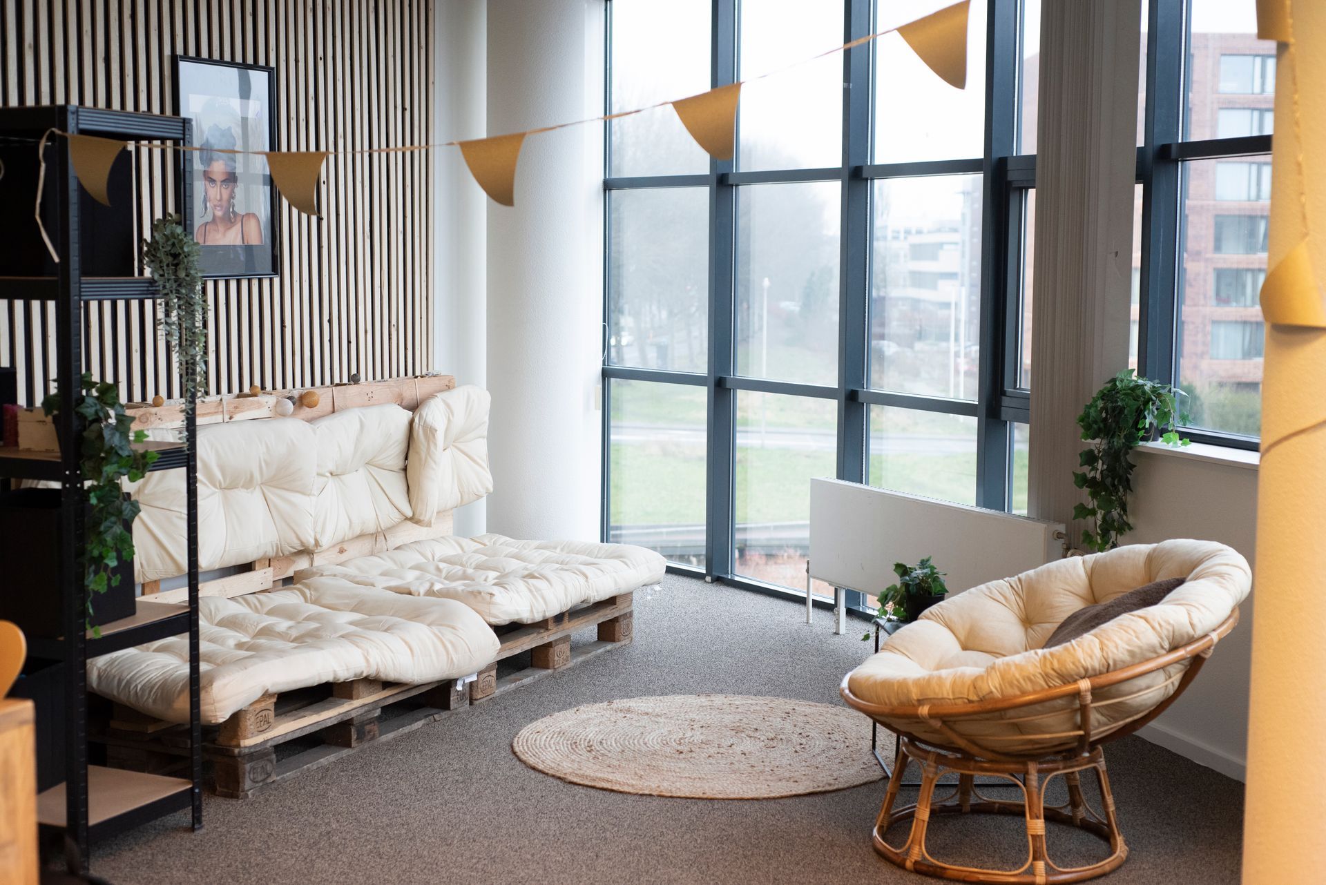 Een woonkamer met een bank en een stoel voor een groot raam.