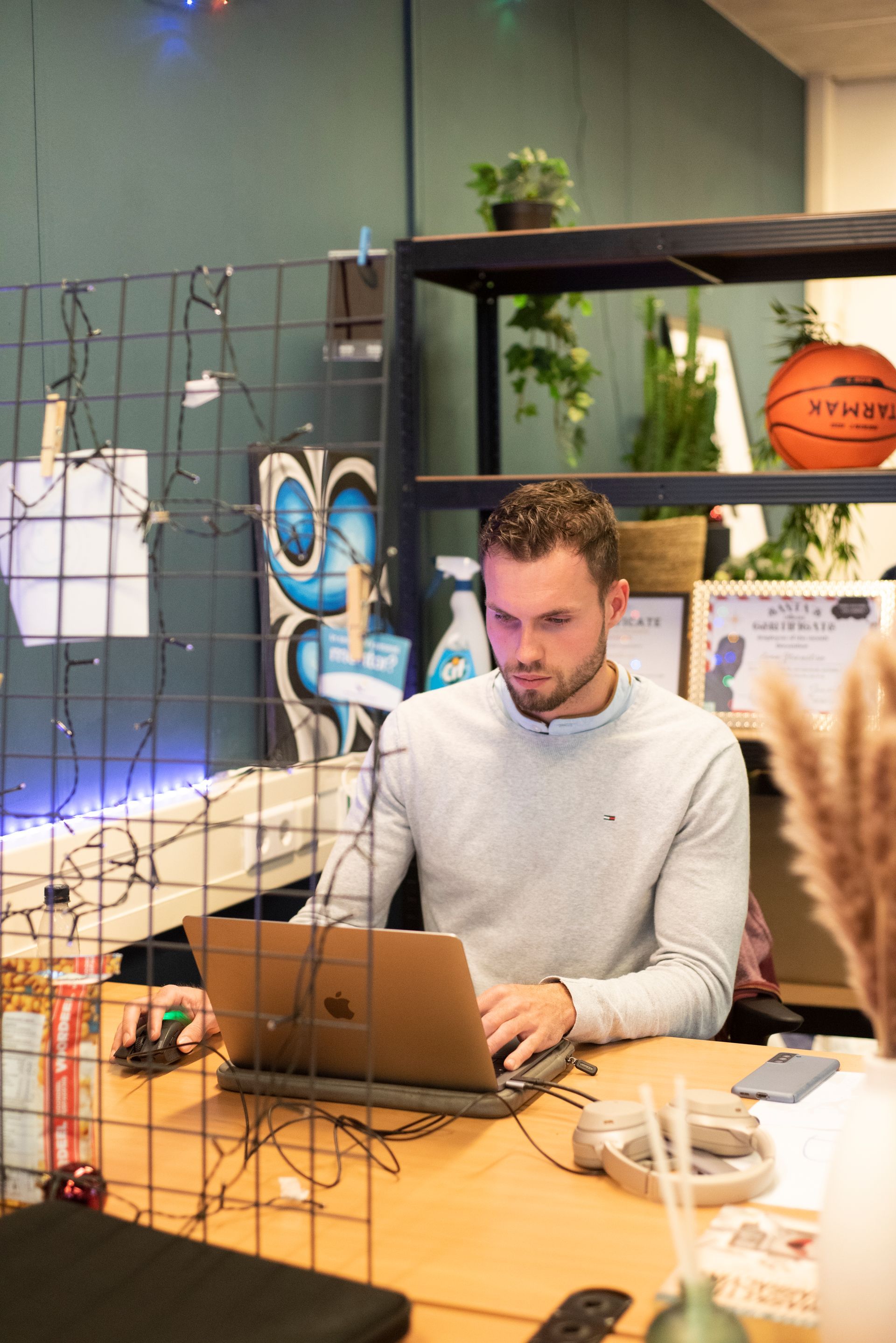 Een man zit aan een bureau en gebruikt een laptop.