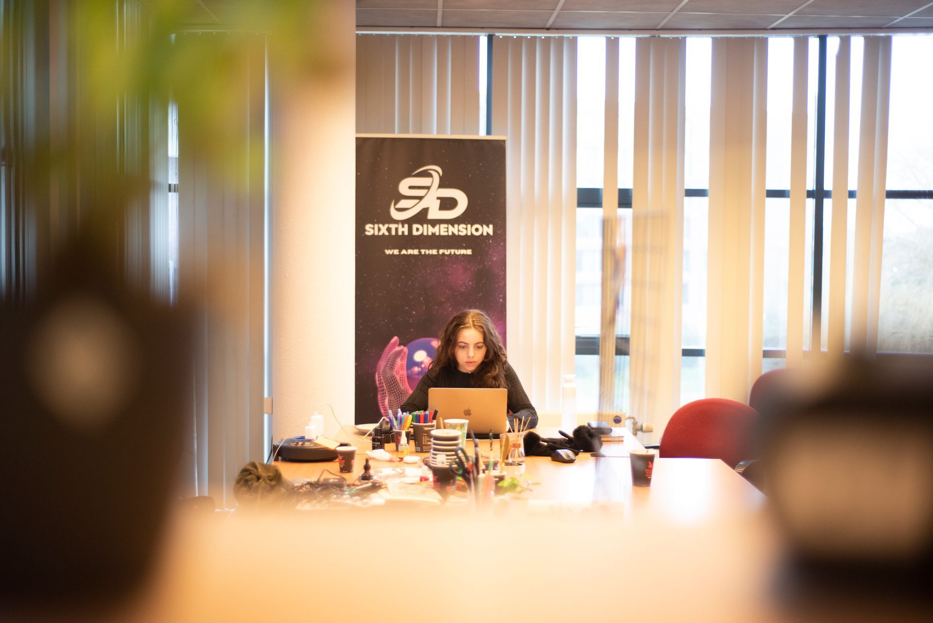 Een vrouw zit aan een bureau voor een laptop.
