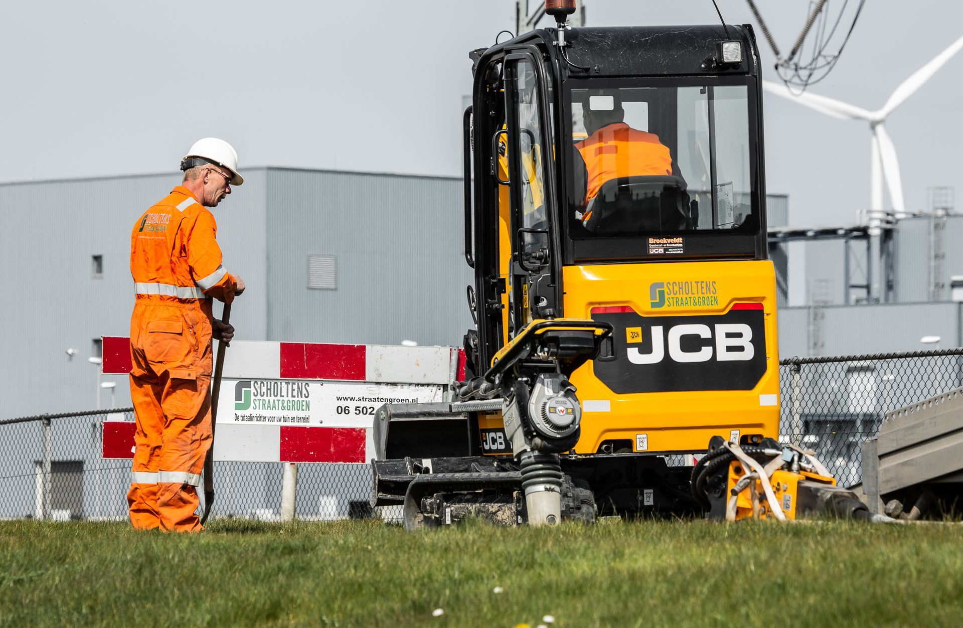 Een man staat voor een gele JCB-bulldozer.