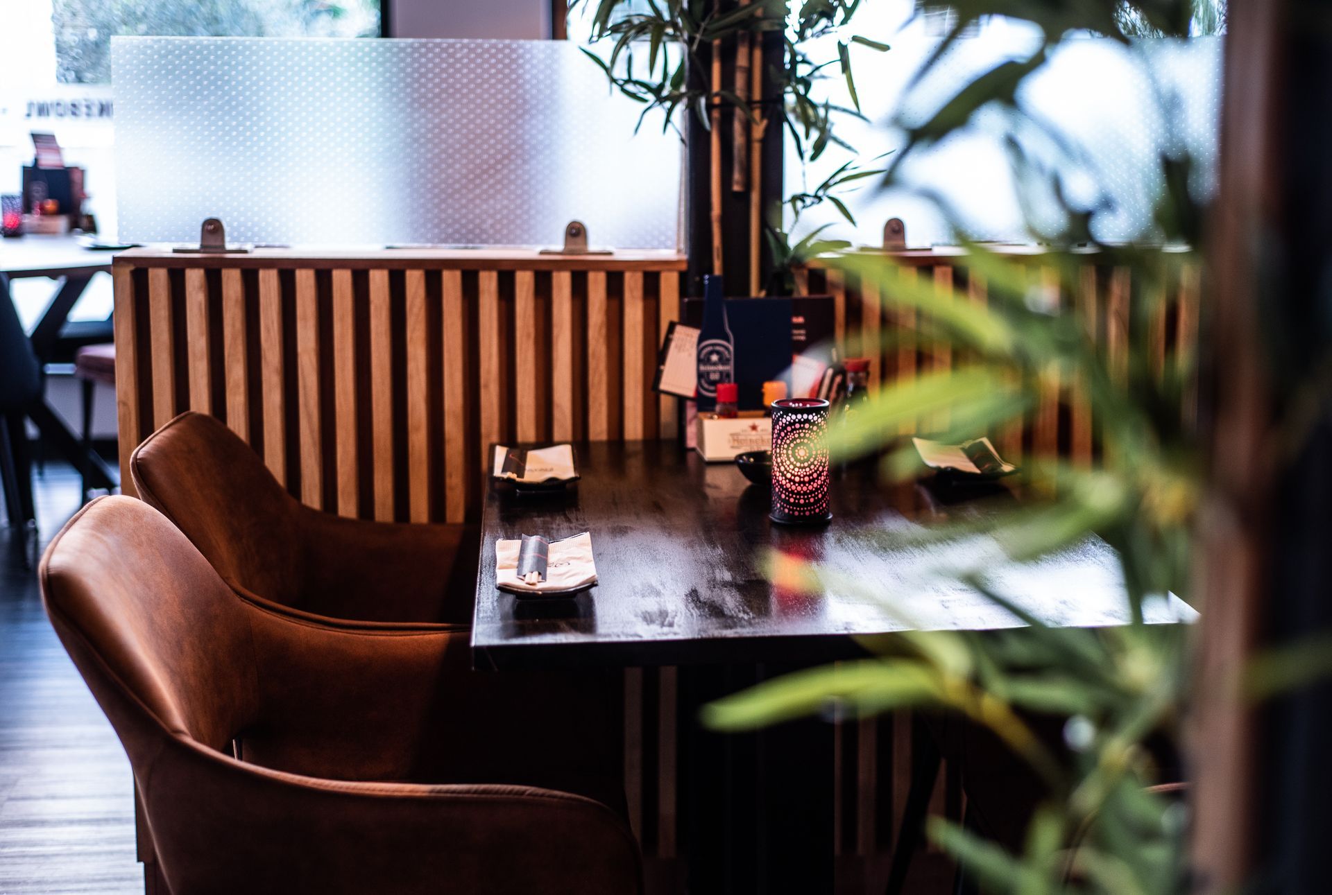 Een restaurant met tafels, stoelen en een plant op de voorgrond.